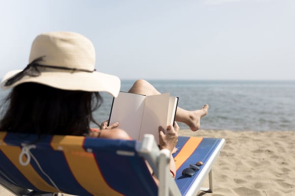 mujer en la playa leyendo un libro