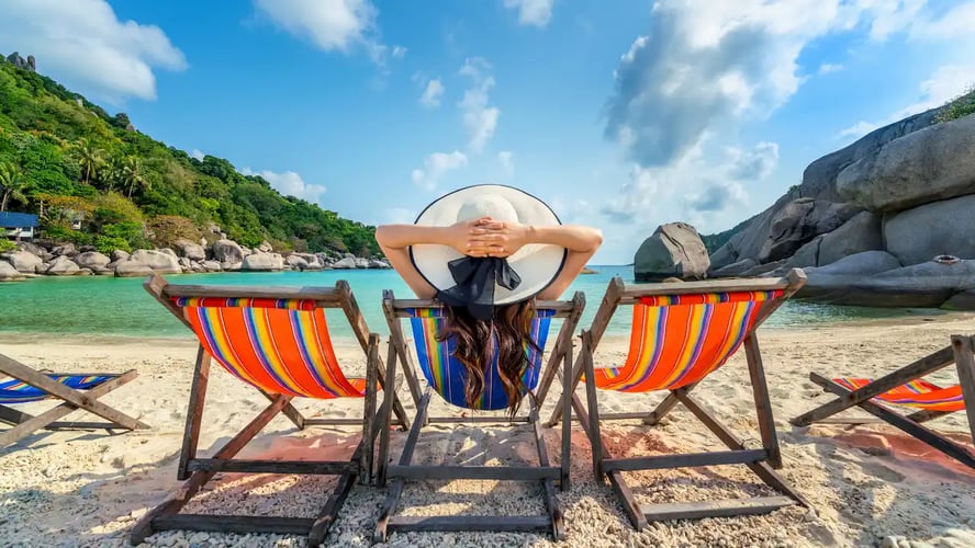 mujer en playa con sombrero sentada en silla